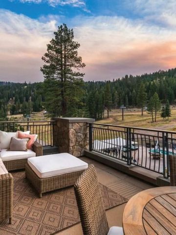Terrasse mit bequemen Sitzmöbeln und Blick auf bewaldete Berge bei Sonnenuntergang