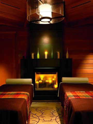 Stimmungsvolles Spa mit Massageliegen und Kamin in warmem Holzdesign
