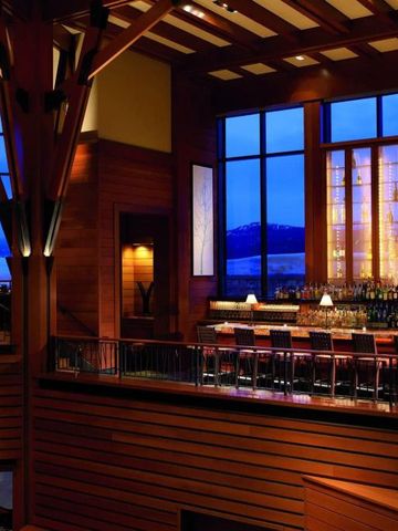 Stilvolle Innenbar mit hohen Fenstern und Blick auf die Berge