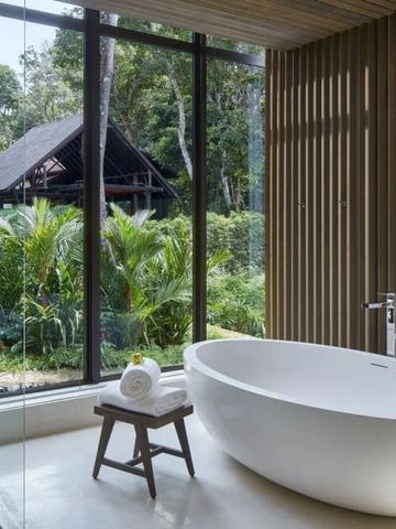 Minimalistisches Badezimmer mit freistehender Badewanne und Fenstern mit Blick ins Grüne