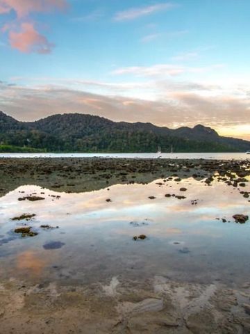 Küstenpanorama mit ruhigem Meer und bewaldeten Hügeln bei Sonnenaufgang