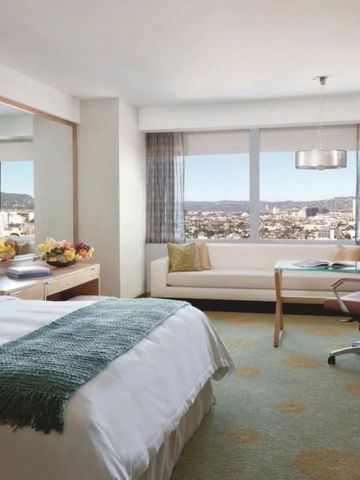 Helles Hotelzimmer mit Doppelbett, Sitzbereich und Blick auf die Stadt