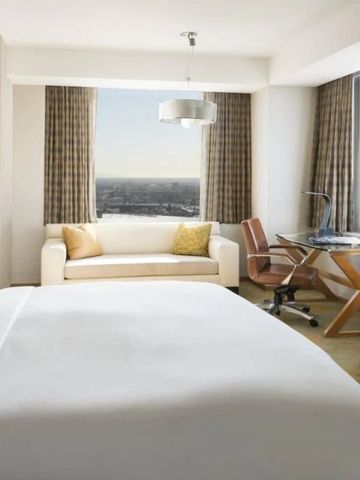 Modernes Zimmer mit großem Bett und Schreibtisch vor dem Fenster