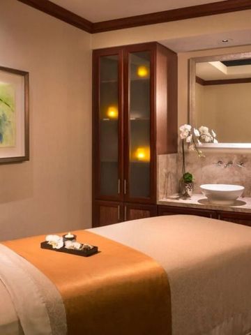 Eleganter Spa-Behandlungsraum mit warmer Beleuchtung und Orchideen auf dem Tisch