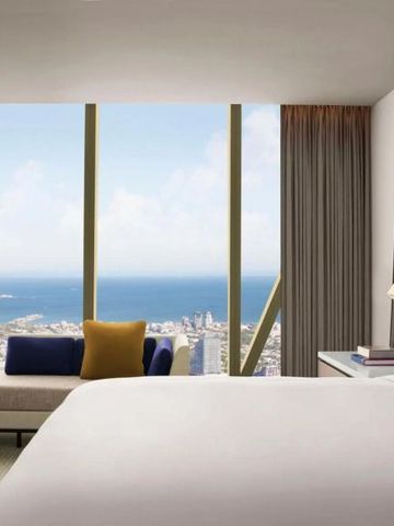 Hotelzimmer mit großem Fenster und Blick auf die Küstenlinie und den Ozean.