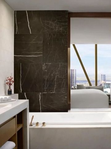 Luxuriöses Badezimmer mit Badewanne und Blick durch Fenster ins Hotelzimmer.