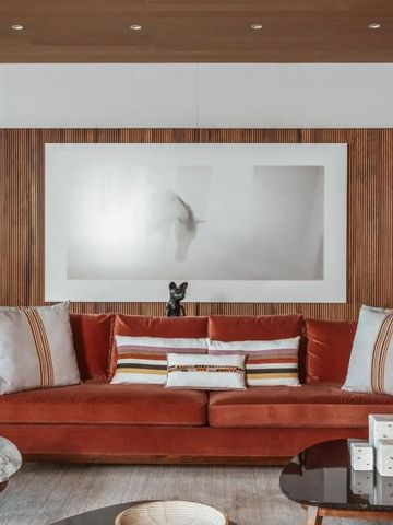 Stilvolles Wohnzimmer mit Designer-Sofa in warmen Farben und Holzwandpaneelen