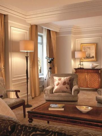 Helles Wohnzimmer einer Suite mit eleganter Einrichtung und Fernglas am Fenster