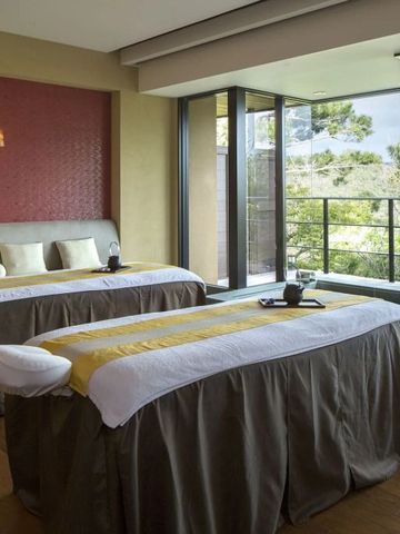 Wellnessbereich mit zwei Massagebetten und Blick auf die grüne Umgebung.