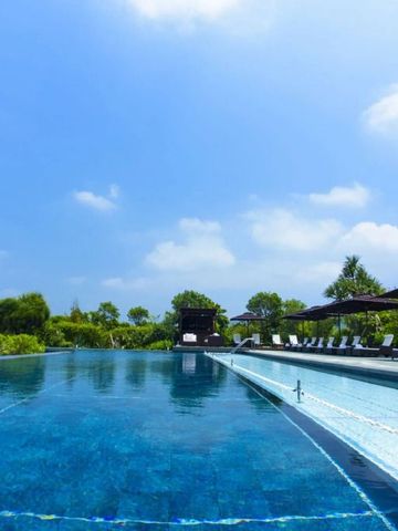 Großer Außenpool mit Liegen und Sonnenschirmen unter klarem Himmel