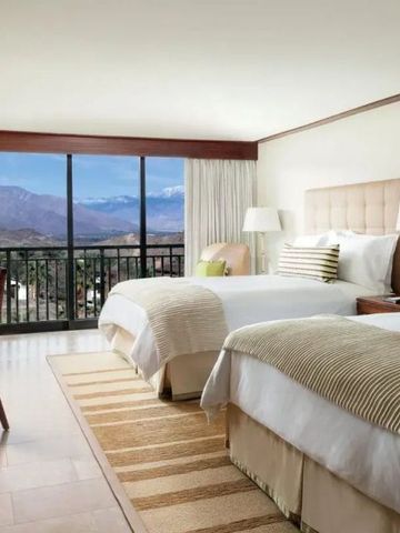 Geräumiges Zimmer mit zwei Betten und Bergblick durch große Fenster.