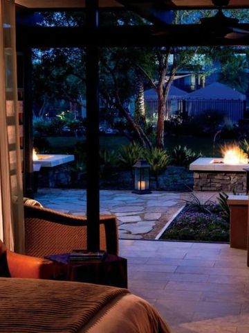 Gemütliches Schlafzimmer mit direktem Zugang zum beleuchteten Garten abends.