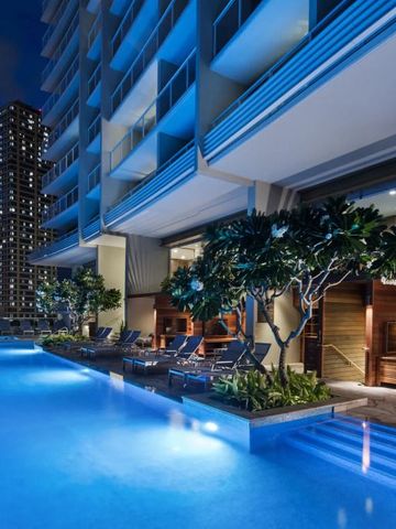 Abendstimmung am beleuchteten Infinity-Pool mit Stadtblick