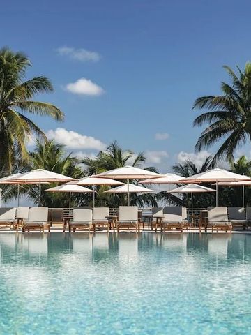 Erfrischender Außenpool mit Palmen und Liegestühlen unter Sonnenschirmen