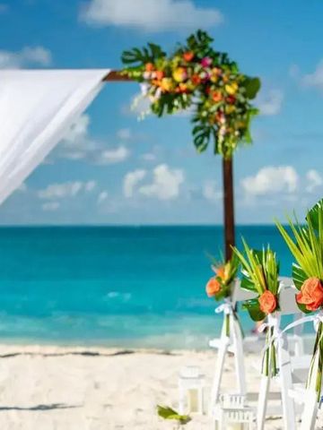 Stranddekoration für eine Hochzeit mit Blumen und Stühlen am Meer