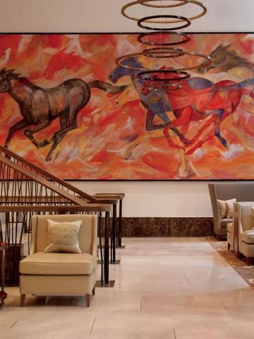 Lobby mit farbenfrohem Gemälde von Pferden und eleganter Sitzgruppe