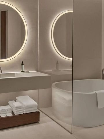 Modernes Badezimmer mit beleuchtetem Spiegel und freistehender Badewanne im Hotel Riviera Maya Kanai