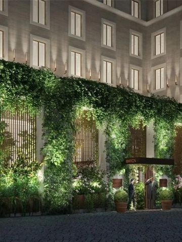 Hotelaußenansicht mit üppiger Pflanzenfassade bei Nachtbeleuchtung