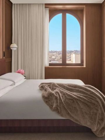 Hotelzimmer mit großem Fenster und gemütlichem Bettblick auf die Stadt