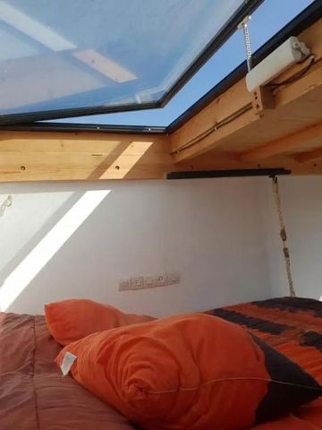 Holzhochbett mit Dachfenster und orangen Kissen