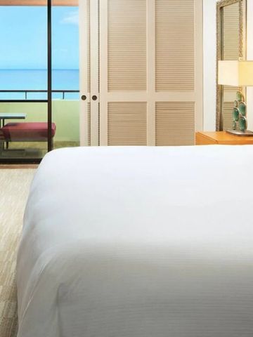 Helles Schlafzimmer in einem Hotel mit Balkon und Blick auf das Meer.