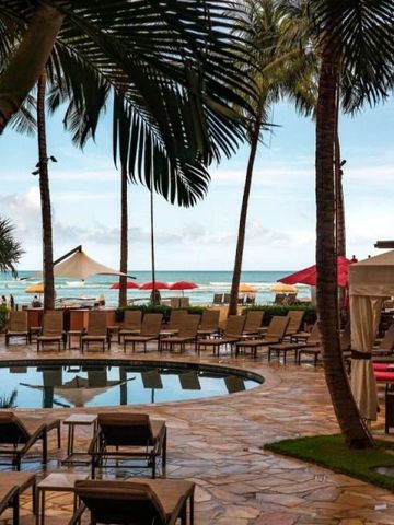 Außenbereich des Hotels mit Palmen und Pool am Strand