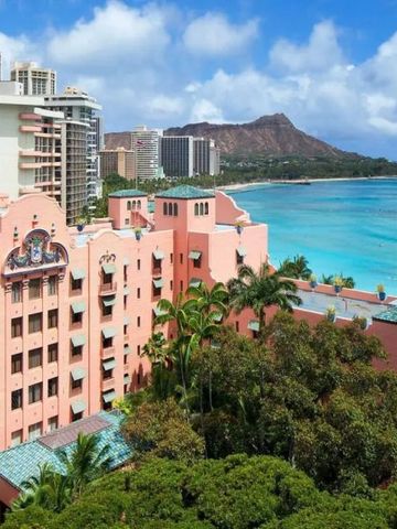 Pinkes Hotelgebäude mit Meerblick und tropischer Vegetation