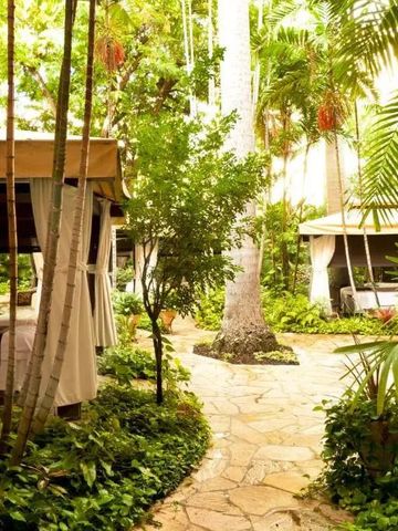 Üppiger tropischer Garten mit hölzernen Cabanas und Steinweg