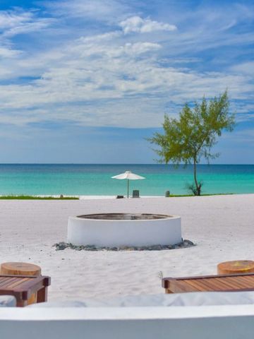 Weißer Sandstrand mit Blick auf das Meer und Liegestühle unter einem klaren blauen Himmel