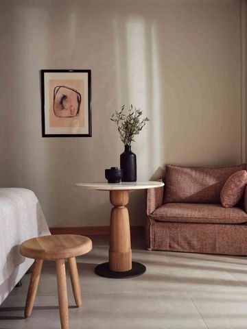 Gemütlicher Loungebereich im Hotelzimmer mit Sessel, Tisch und Kunstwerk