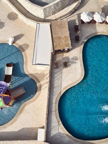 Luftaufnahme von zwei organisch geformten Pools mit Sonnenliegen.