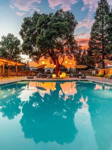 Pool bei Sonnenuntergang umgeben von Bäumen und beleuchteten Sitzbereichen