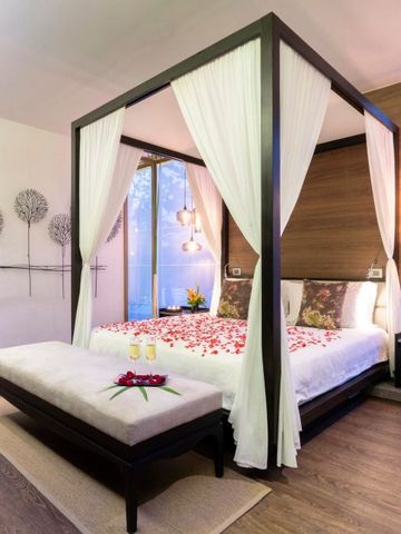 Romantisches Schlafzimmer mit Himmelbett und Blumenarrangement