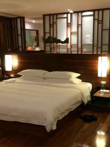 Elegantes Hotelzimmer mit Kingsize-Bett und stilvoller Raumtrennung aus Holz.