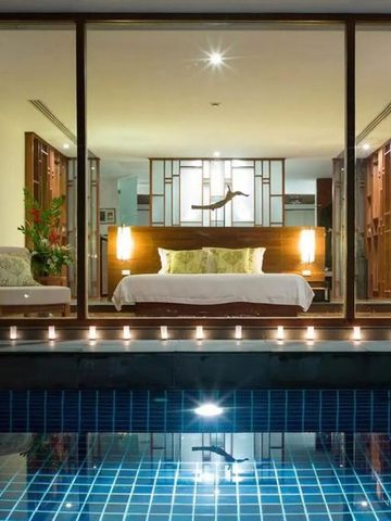 Zimmer mit Blick auf beleuchteten Pool durch große Glaswand.