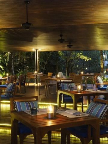 Beleuchteter Restaurantbereich im Freien mit gemütlichen Tischen bei Nacht.