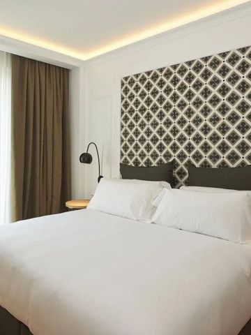 Gemütliches Schlafzimmer mit elegantem Kopfteil und Balkontüren im Hotel Serras Barcelona