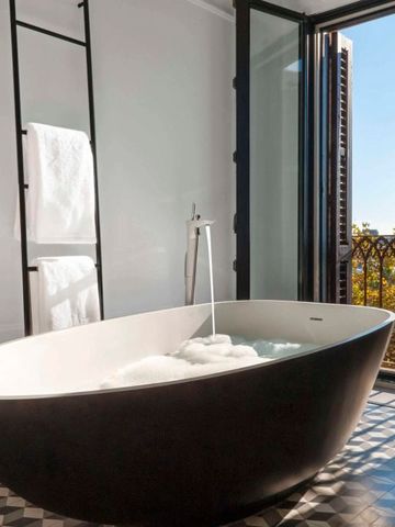 Luxuriöses Badezimmer mit freistehender Badewanne und Balkon im Hotel Serras Barcelona