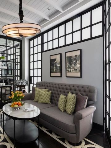 Stilvolle Sitzecke mit Sofa und Couchtisch in einem Zimmer des The Siam Hotels