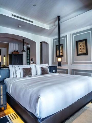 Geräumiges Schlafzimmer im The Siam Hotel mit kunstvollen Wandverzierungen