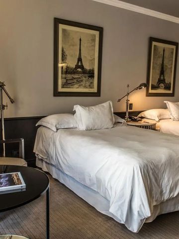 Doppelzimmer mit zwei Betten und stilvollen Pariser Fotografien.