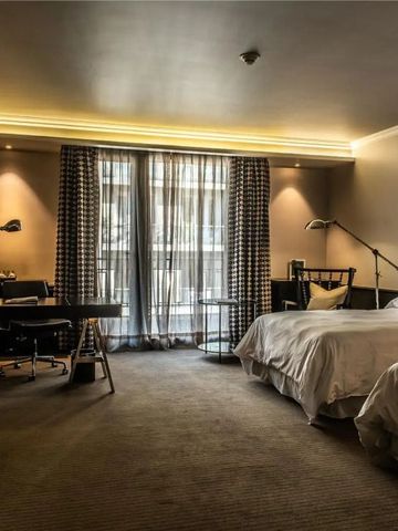 Geräumiges Hotelzimmer mit zwei Betten, modernem Schreibtisch und großen Fenstern.