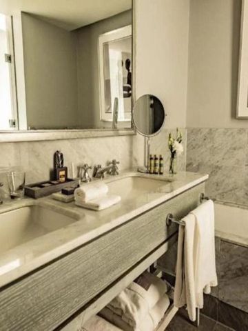 Geräumiges Badezimmer mit elegantem Waschbecken und Marmorverzierungen.