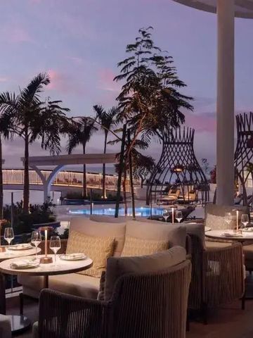 Strandrestaurant mit stilvoller Beleuchtung bei Sonnenuntergang und tropischen Palmen