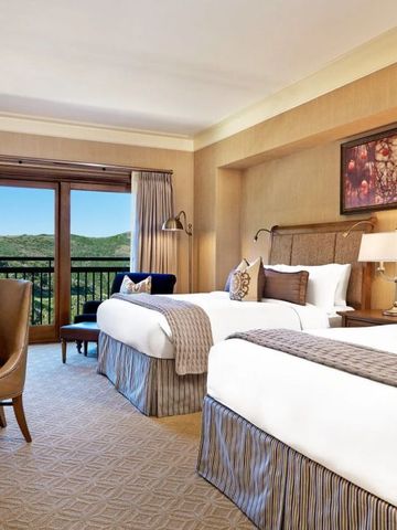 Geräumiges Doppelzimmer mit zwei Betten, Kamin und Balkonblick auf die Berge.