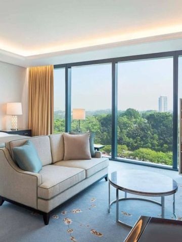 Helles Hotelzimmer mit Panoramafenster, eleganter Einrichtung und Blick ins Grüne.