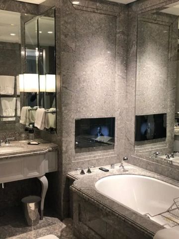 Elegantes Badezimmer in grauem Marmor mit Badewanne und großen Spiegeln