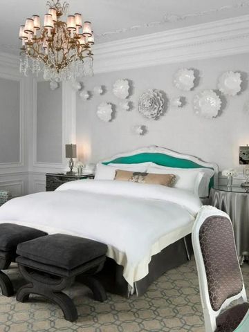 Helles Schlafzimmer im St. Regis New York mit verzierten weißen Wänden und einem Kronleuchter.