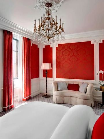 Hotelzimmer mit roten Wänden und luxuriösem Kronleuchter