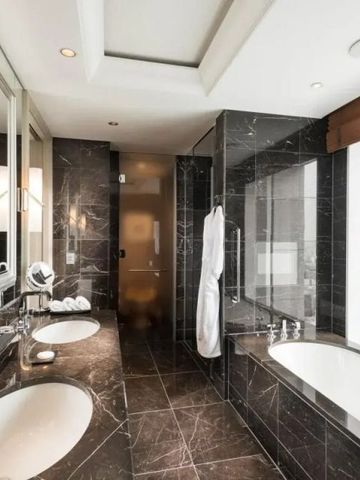 Badezimmer mit Marmorausstattung und großer Fensterfront mit Stadtblick